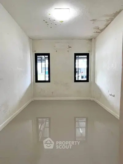 Spacious empty room with glossy tiled floor and two windows, ideal for customization.