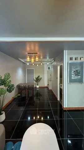 Modern living room with sleek black tile flooring and stylish lighting fixtures.