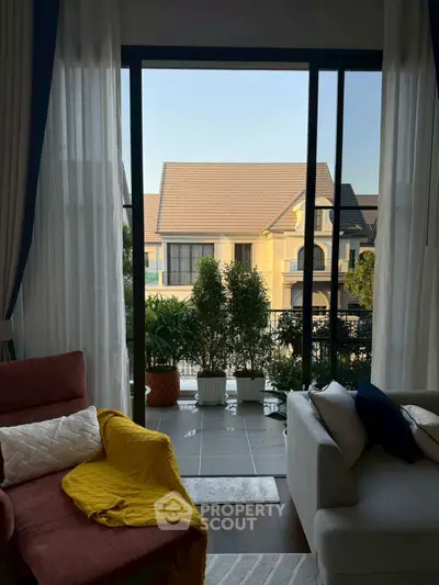 Charming living room with cozy seating and balcony view of elegant neighborhood.