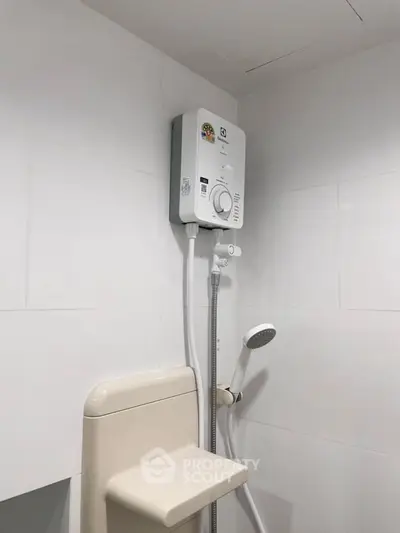 Modern bathroom with sleek white tiles and a compact water heater.