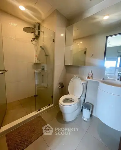 Modern bathroom with glass shower and sleek fixtures in contemporary apartment.