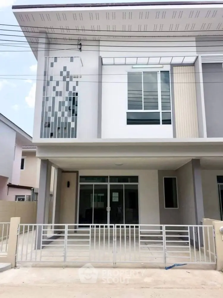 Modern two-story house with sleek facade and gated driveway