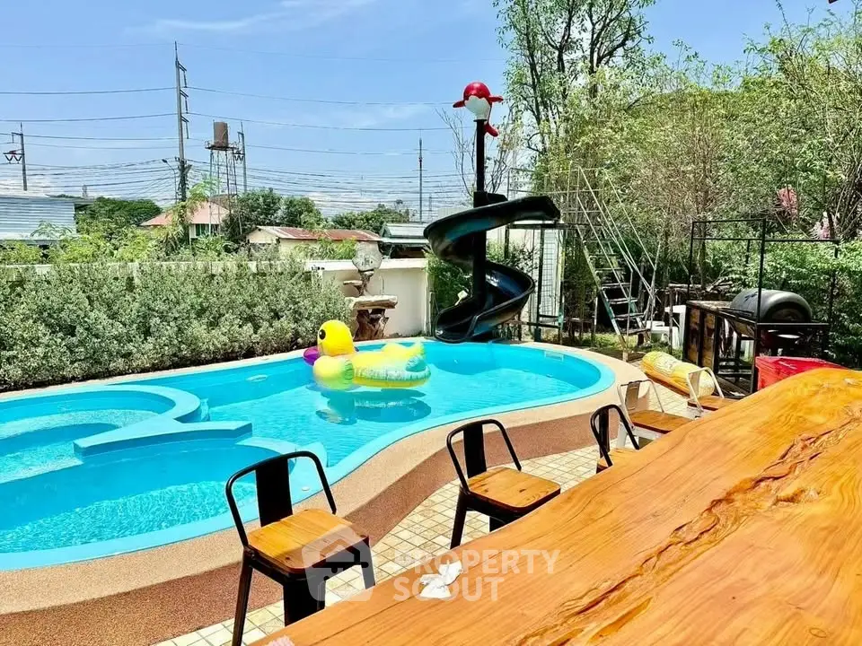 Charming outdoor pool area with slide and seating, perfect for relaxation and entertainment.