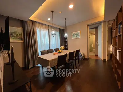 Elegant dining space with rich wooden flooring, modern chandelier, and a large table set for a family meal, adjacent to a cozy living area.