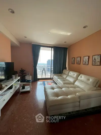 Spacious living room with modern white sofa and city view balcony, perfect for relaxation.