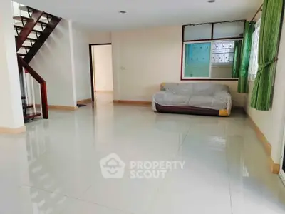 Spacious living room with modern staircase and natural light, perfect for family gatherings.