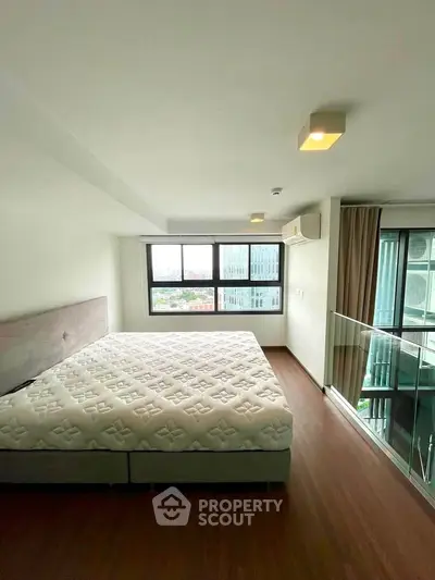 Spacious bedroom with large window offering stunning city views in modern apartment.