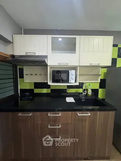 Modern kitchen with sleek cabinetry and built-in microwave, featuring a stylish backsplash and compact design.