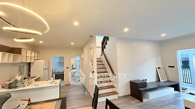 Modern open-plan living area with stylish lighting and staircase, perfect for contemporary living.