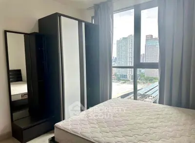 Modern bedroom with city view, featuring a large window, wardrobe, and bed frame in a high-rise apartment.