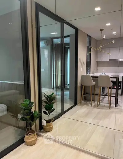 Modern apartment interior with mirrored walls and sleek kitchen design, featuring stylish bar stools and contemporary lighting.