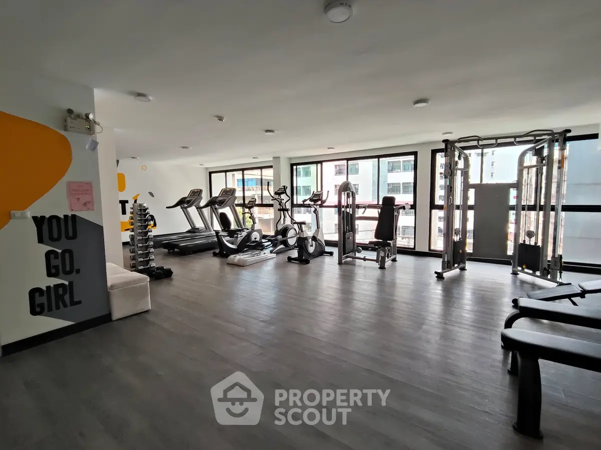 Spacious modern gym with large windows and fitness equipment in a residential building.