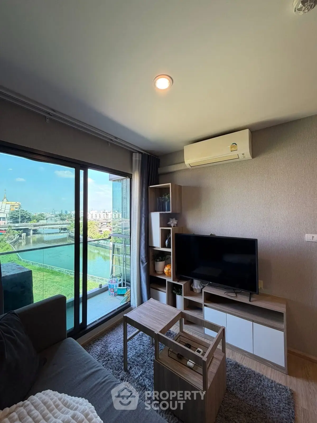 Modern living room with balcony view overlooking a scenic river, featuring stylish furniture and natural light.