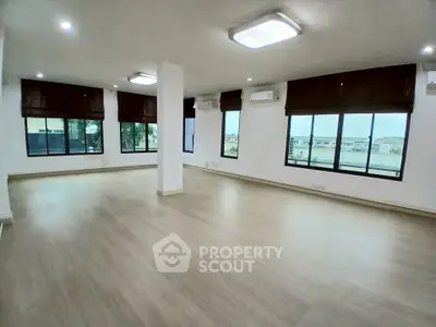 Spacious open-plan living room with large windows and wooden flooring, ideal for modern living.