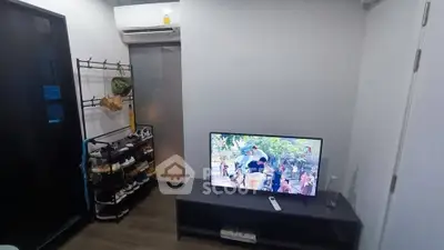 Cozy living room with modern TV setup and shoe rack, perfect for relaxation.