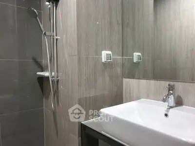 Modern bathroom with sleek sink and shower in elegant gray tiles.