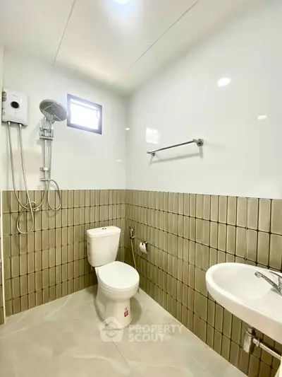 Modern bathroom with shower, toilet, and sink in a bright, tiled space.