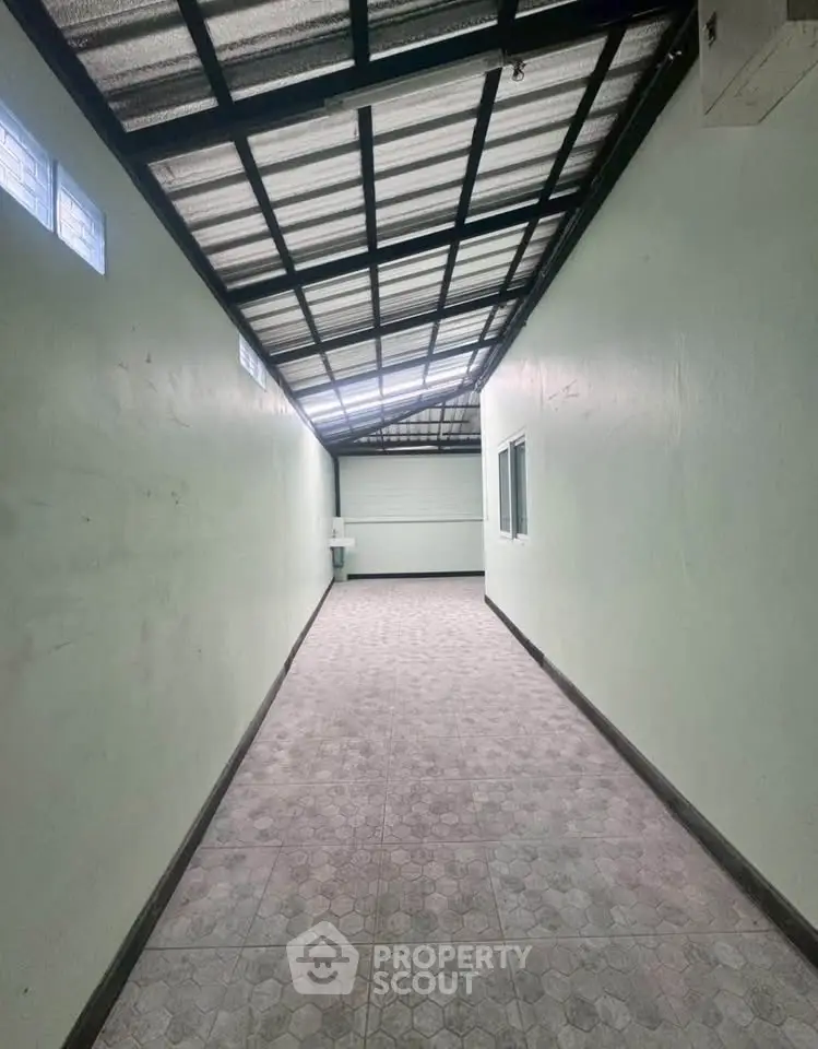 Spacious corridor with tiled flooring and metal roof, ideal for storage or utility use.
