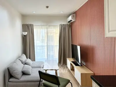Modern living room with stylish furniture and natural light, featuring a cozy sofa and sleek TV setup.