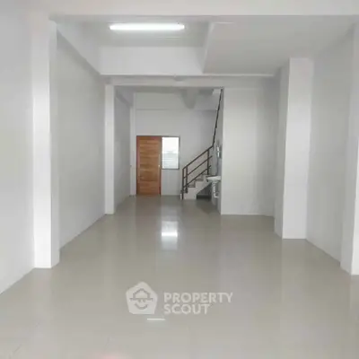 Spacious open-plan interior with modern staircase and sleek tile flooring, perfect for versatile living or office space.