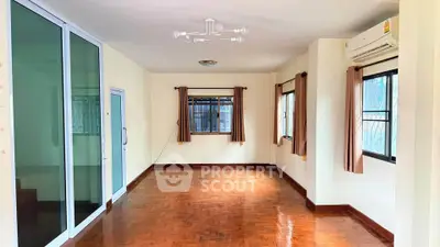 Spacious living room with hardwood floors and large windows in a modern apartment.
