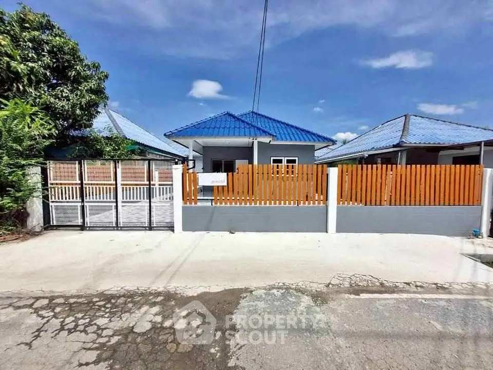 Charming single-story home with blue roof and wooden fence in sunny neighborhood.