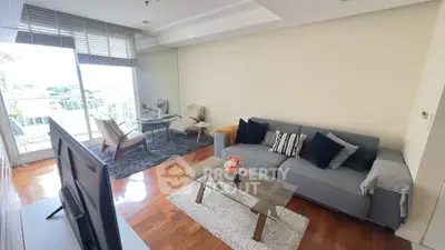 Spacious living room with modern decor and large windows offering natural light and a view.