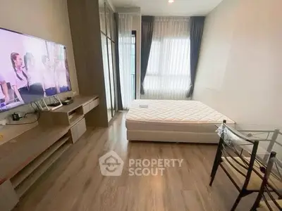 Modern studio apartment with sleek design, featuring a cozy bed, flat-screen TV, and stylish glass table.