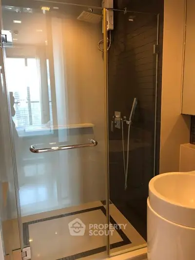 Modern bathroom with glass shower enclosure and sleek fixtures in a high-rise apartment.