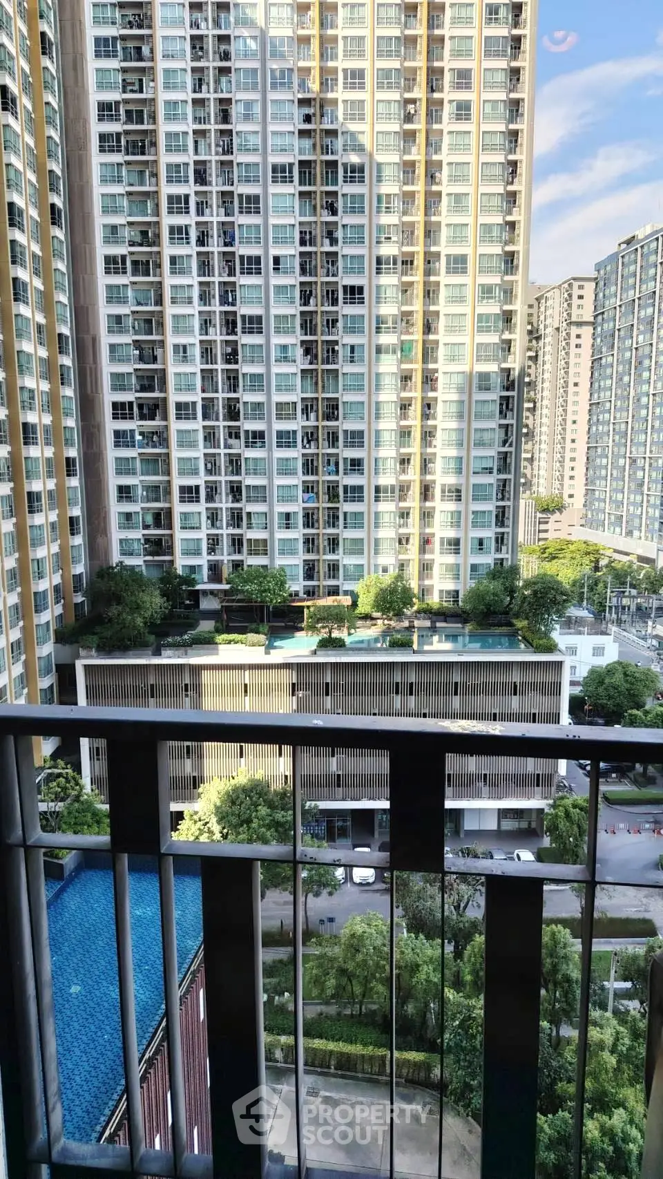 Stunning urban view from a high-rise balcony overlooking modern residential buildings and lush greenery.