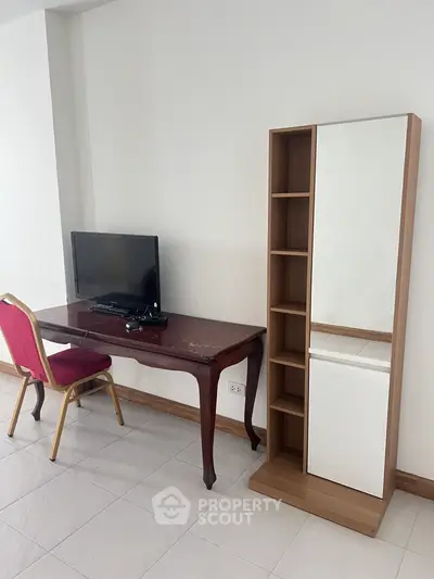 Modern apartment interior with TV, desk, and shelving unit for stylish living.