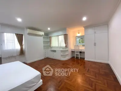 Spacious bedroom with elegant wooden flooring and built-in storage solutions.