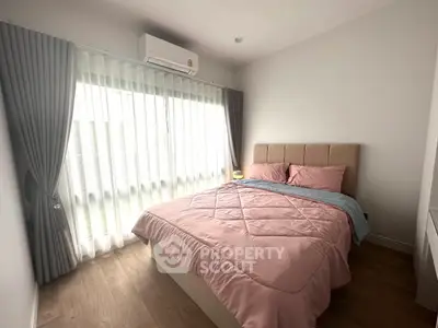 Cozy bedroom with natural light and elegant curtains, featuring a comfortable bed and air conditioning.