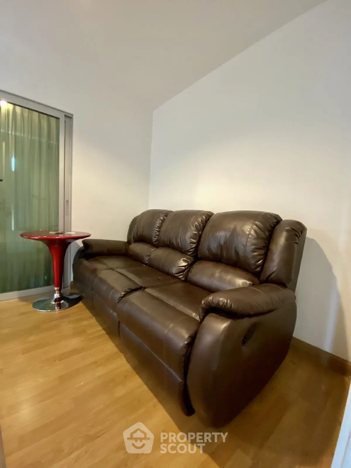 Cozy living room with leather sofa and modern side table on wooden flooring.