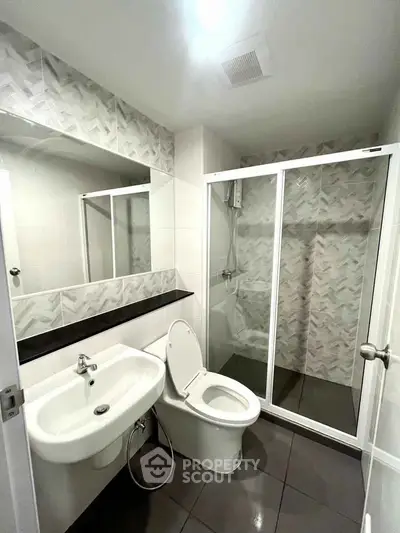 Modern bathroom with sleek shower enclosure and stylish sink in contemporary apartment.