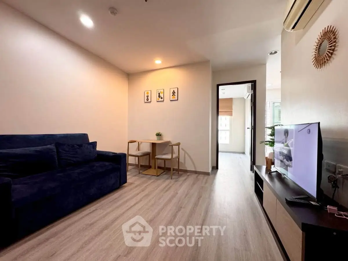 Modern living room with stylish decor and open layout, featuring a cozy sofa and flat-screen TV.