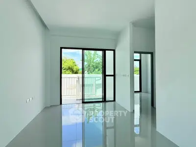 Spacious modern living room with large windows and balcony access, offering abundant natural light and serene views.