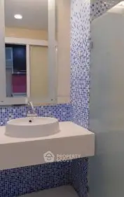 Modern bathroom with stylish blue mosaic tiles and sleek white sink.