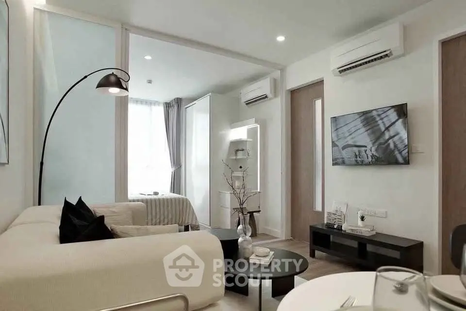 Modern living room with sleek design and neutral tones, featuring a cozy seating area and wall-mounted TV.