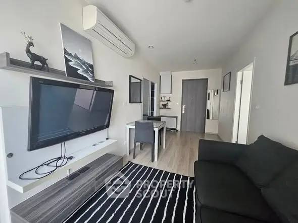 Modern living room with sleek decor, large TV, and open layout in stylish apartment.
