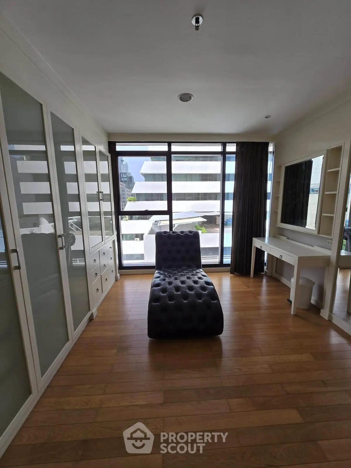 Spacious modern bedroom with large windows and stylish furniture in urban apartment.