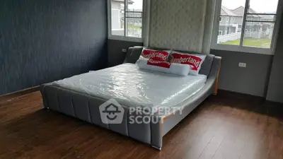 Spacious bedroom with modern bed and large windows offering natural light.