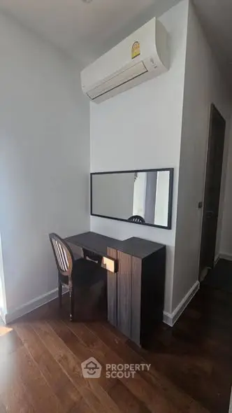 Modern study nook with desk, chair, and wall-mounted air conditioner in a stylish apartment.
