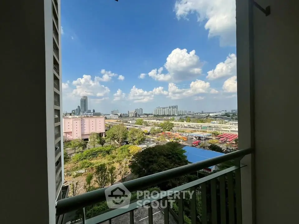 Stunning cityscape view from a high-rise balcony with lush greenery and blue skies.