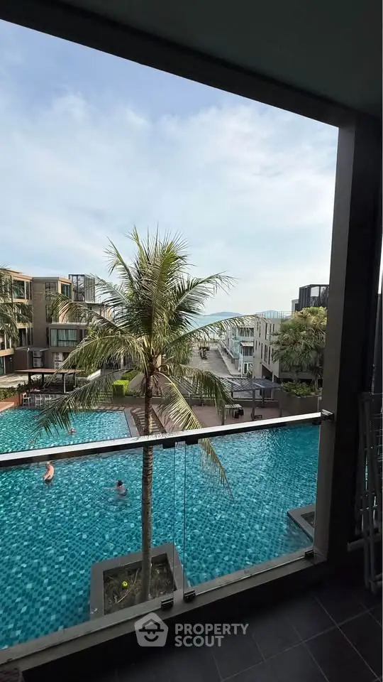 Luxurious poolside view from balcony with palm trees and modern architecture.