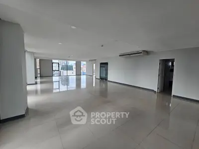 Spacious open-plan living area with large windows and tiled flooring in modern apartment.