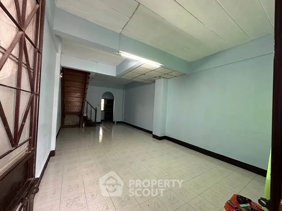 Spacious empty living room with staircase and tiled flooring