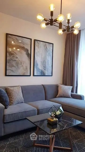 Stylish living room with modern decor, featuring a cozy gray sofa, chic lighting, and elegant wall art.