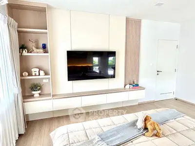 Modern bedroom with sleek TV unit and cozy decor, featuring natural light and stylish furnishings.