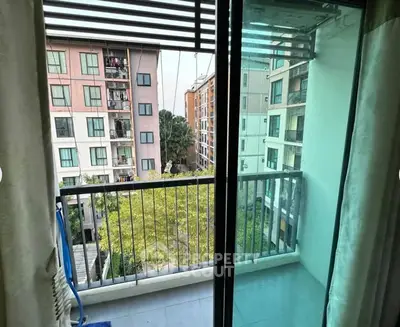 Charming balcony view from modern apartment overlooking lush greenery and neighboring buildings.